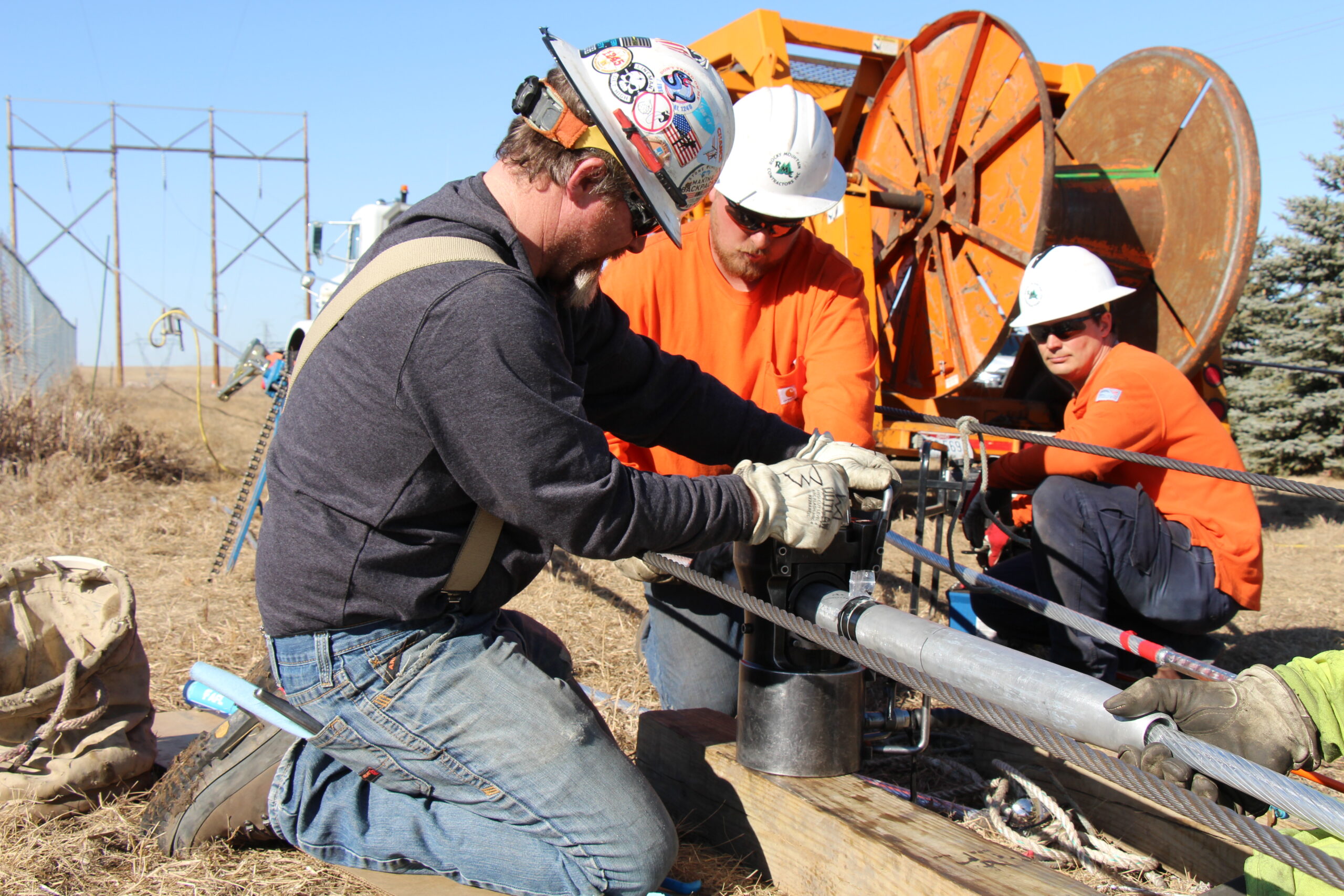 Construction workers replace the wires on a transmission line.