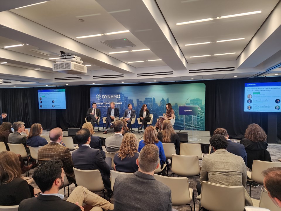 A panel discussion in front of a group of people in front of a backdrop that says Dynamo.