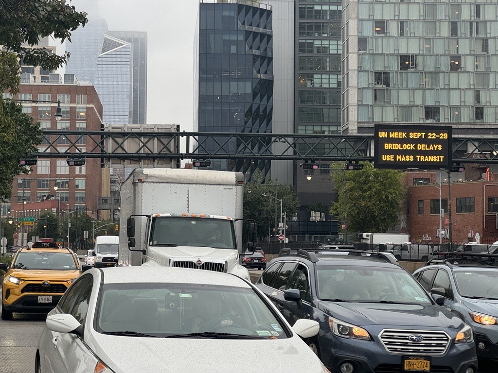 Photo of traffic in NYC, a sign above the traffic warns of gridlock.