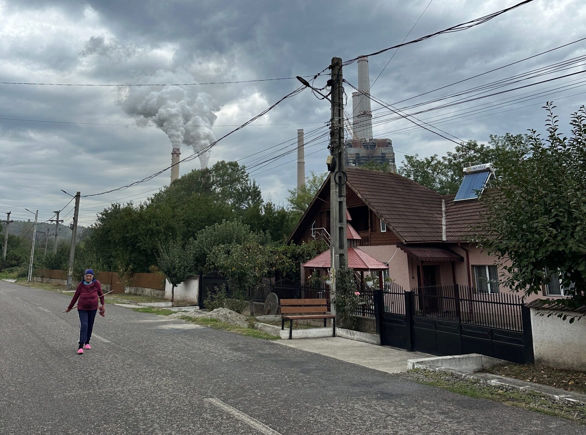 A woman walks on a road in Rovinari with the coal power plant in the background.