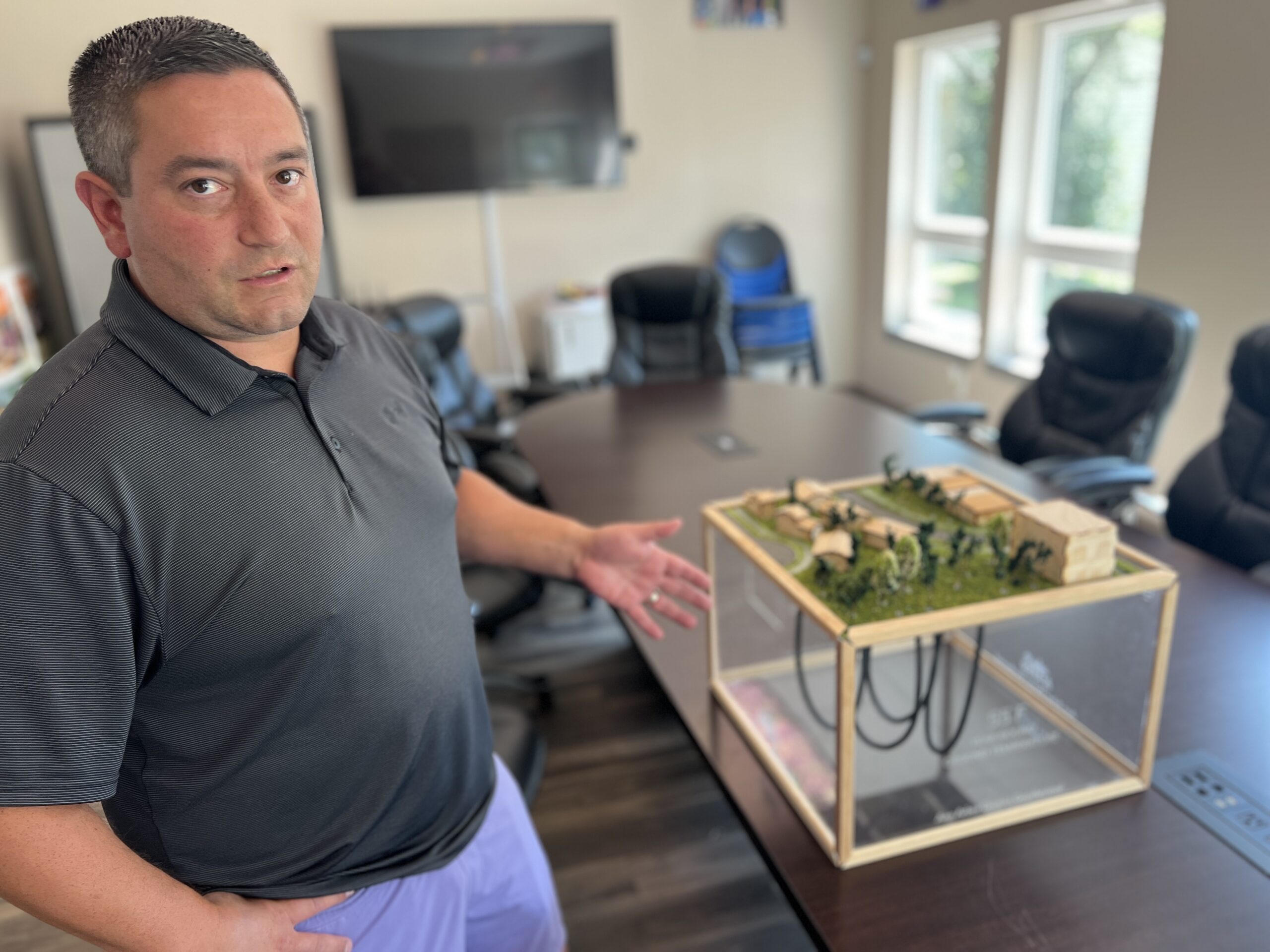 Derrick Miller, who leads the clean energy initiatives in the Bryant Community, stands next to a model of a proposed geothermal energy facility the city is studying for the area.