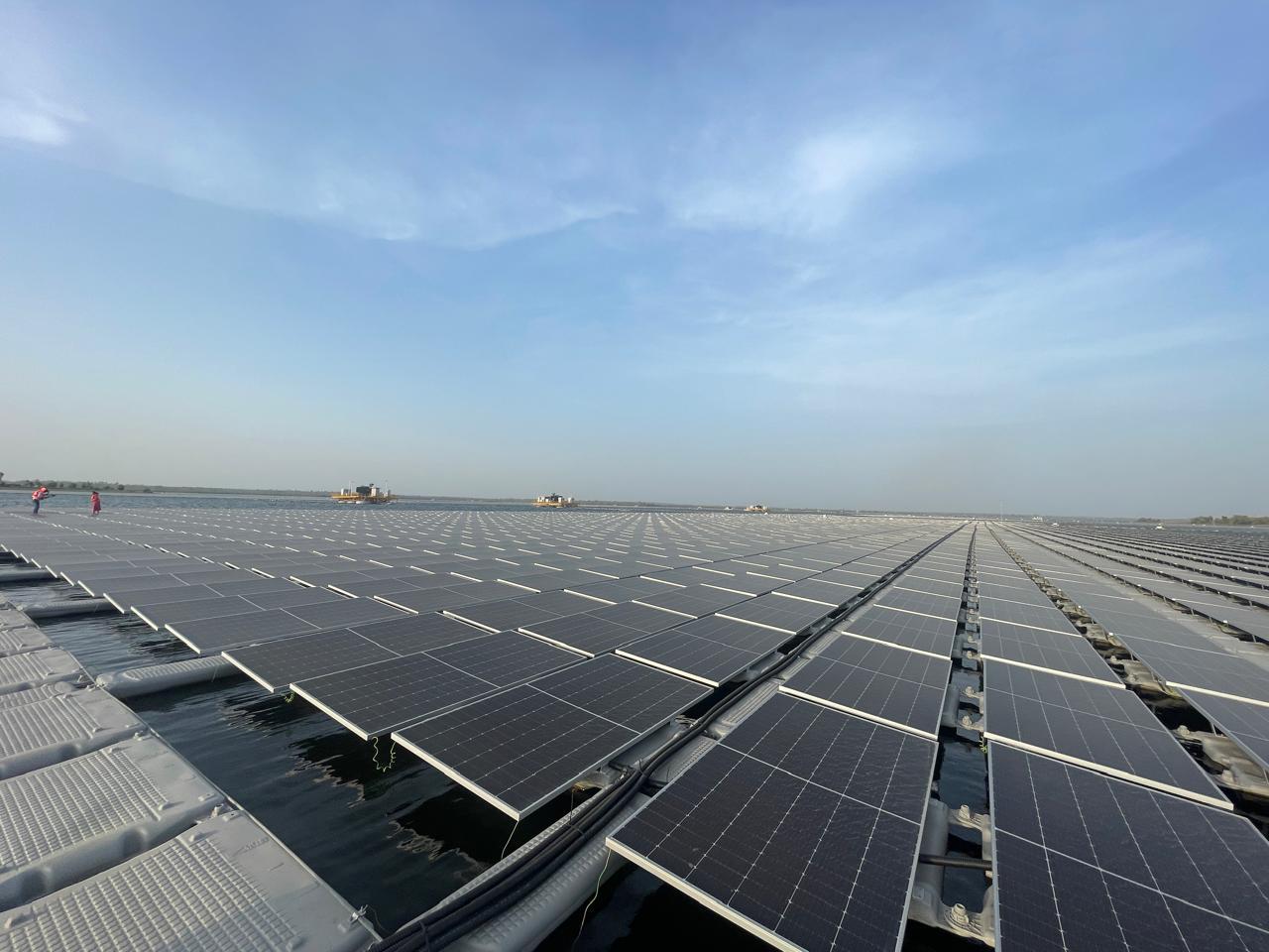 A photo of solar panels floating on the surface of a lake under serene blue skies.