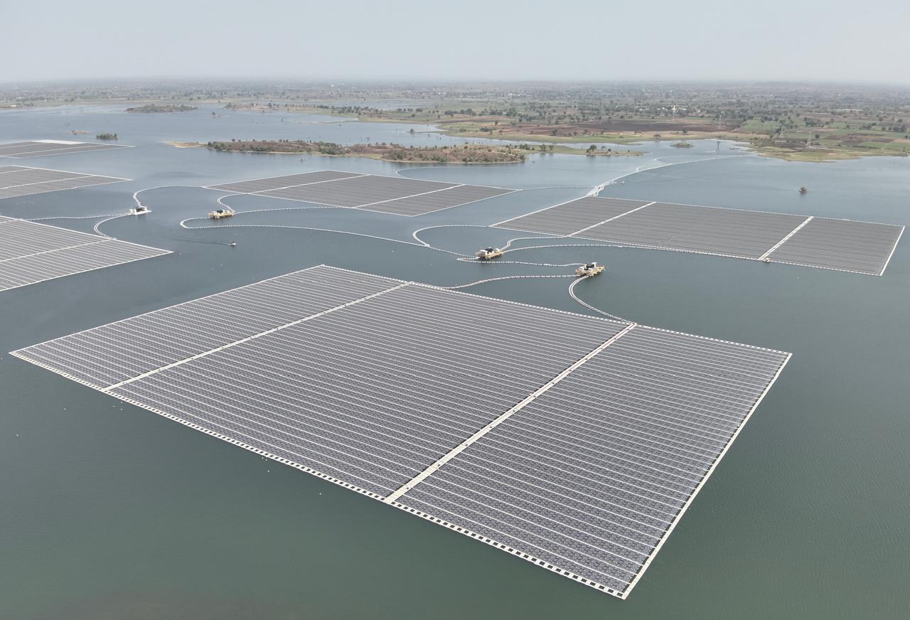 A photo of islands of solar panels floating on a large lake, photo taken from the air.