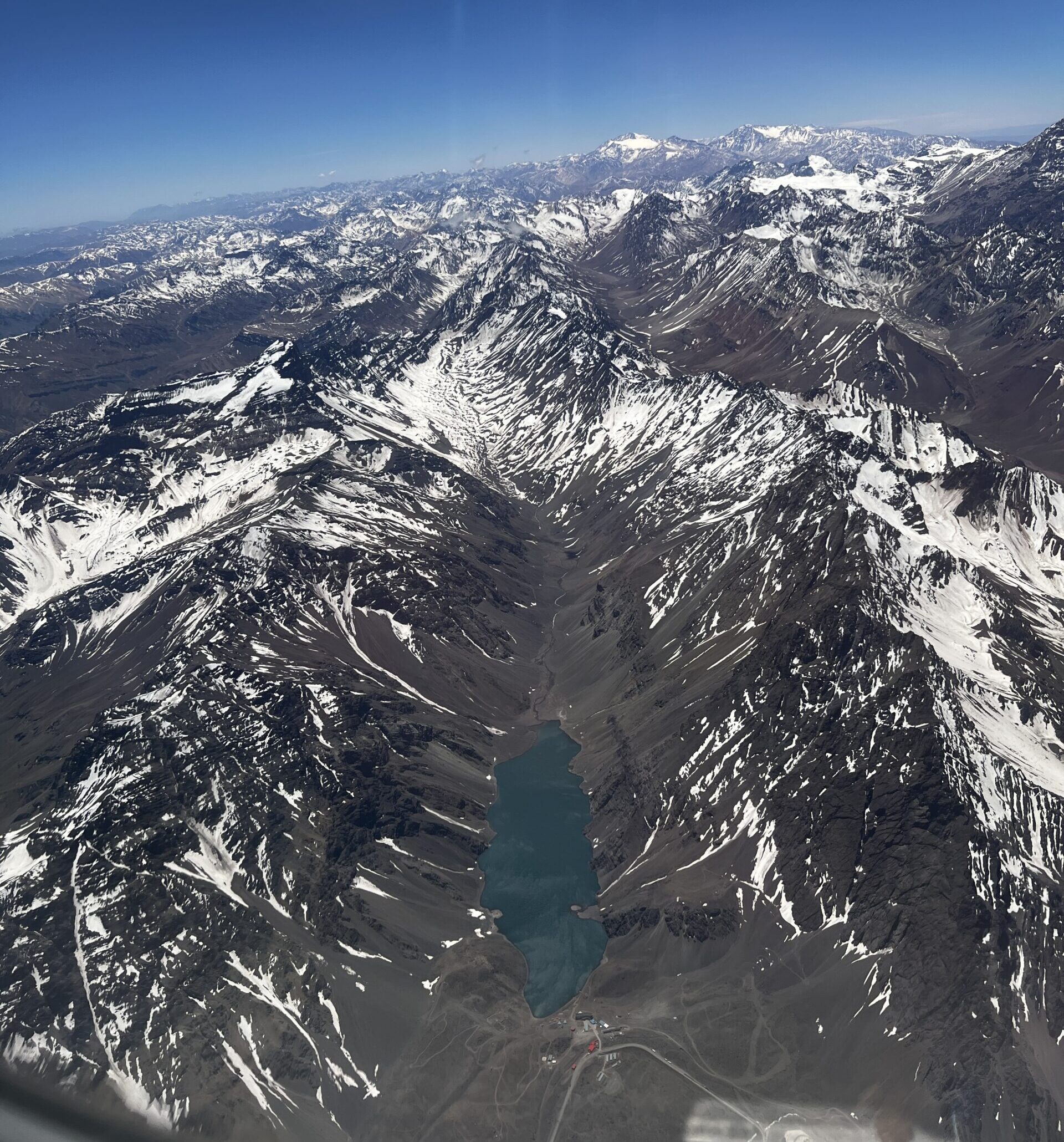 A photo of a lake in a valley nestled between snow-capped mountain ranges from the air.